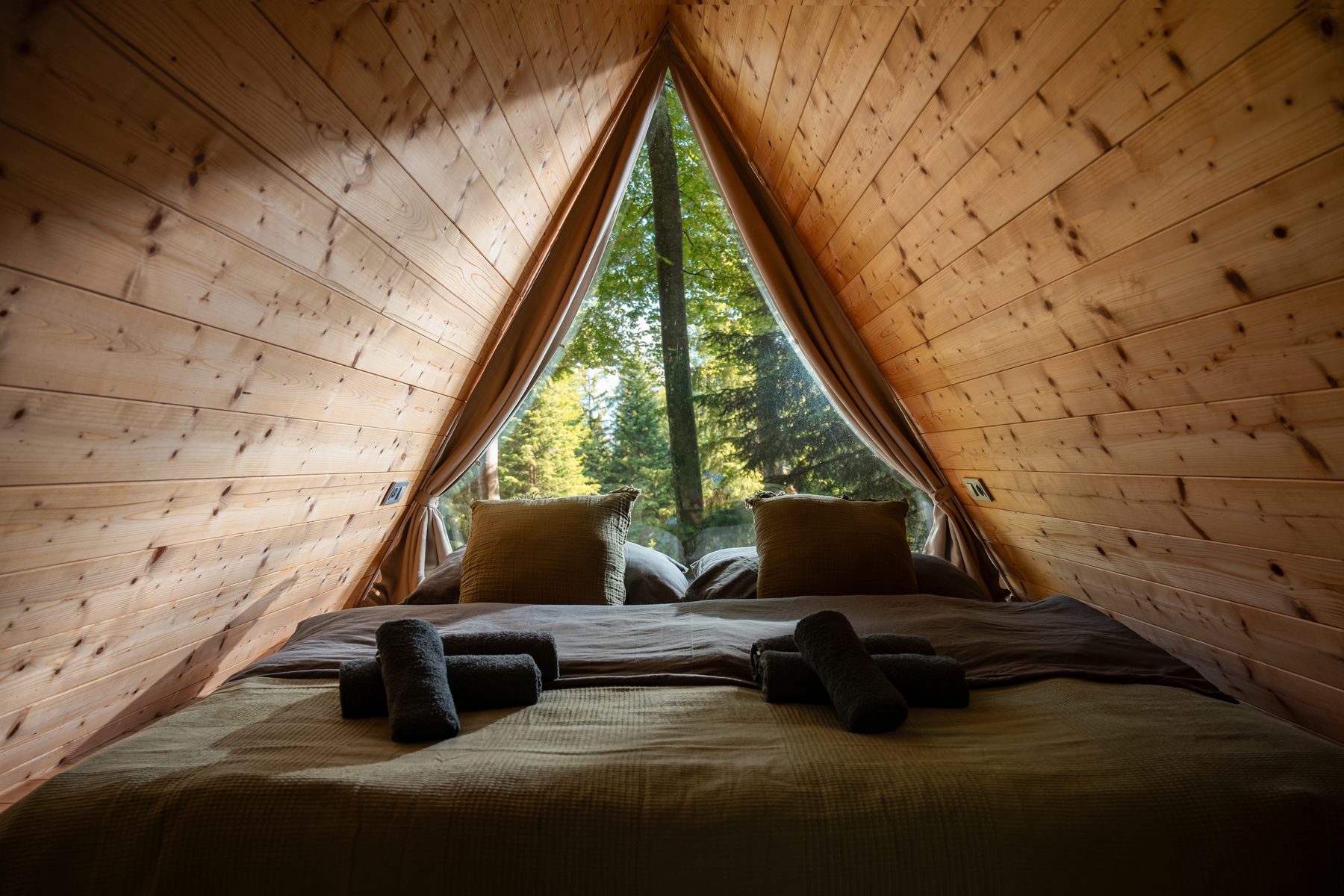 Detail of a wooden cabin interior with linen bedding and soft lamp light