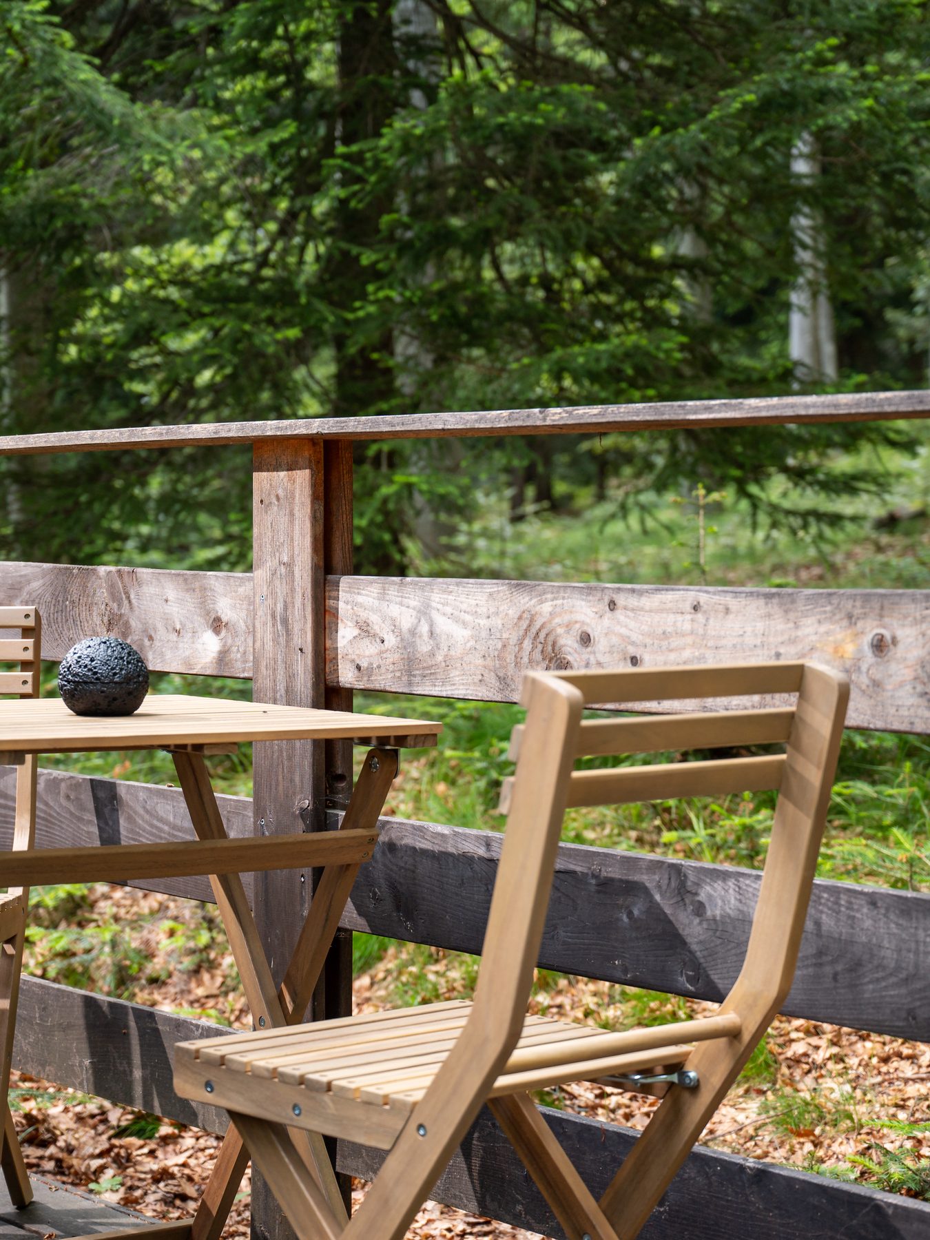 A private wooden terrace with simple furniture facing the forest