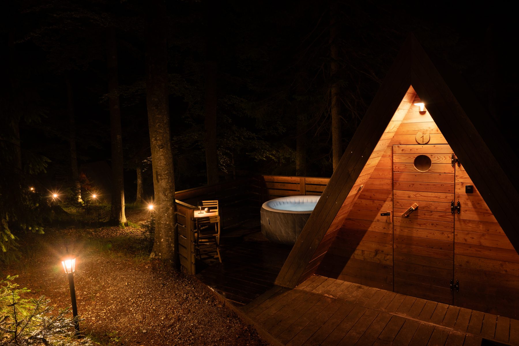 Wooden cabin with a private outdoor hot tub surrounded by trees